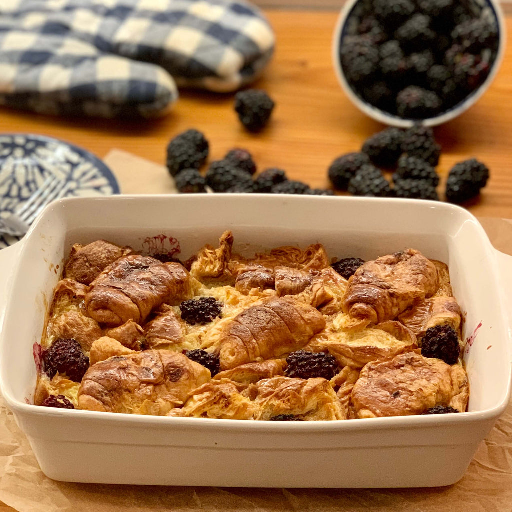 croissant bread pudding in baking dish on table with berries